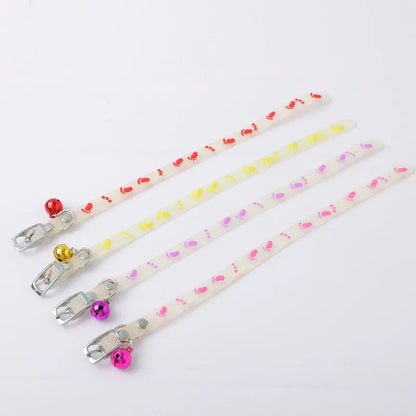 Glowing adjustable luminous collar for cats on a dark background, showing silicone chain and metal bell.