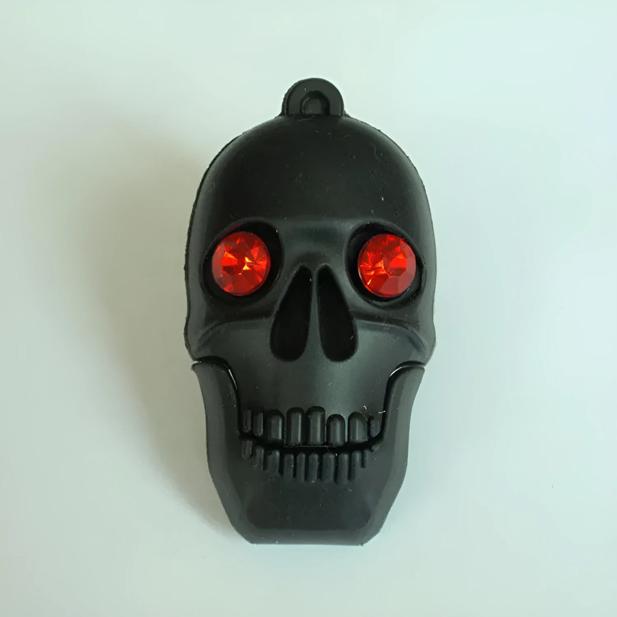 Skull-shaped black USB flash drive on a small metal keychain against a dark background.