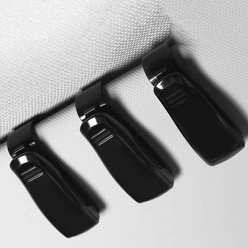 Black plastic clip for car sunshades to hold tickets, ID cards, or glasses.