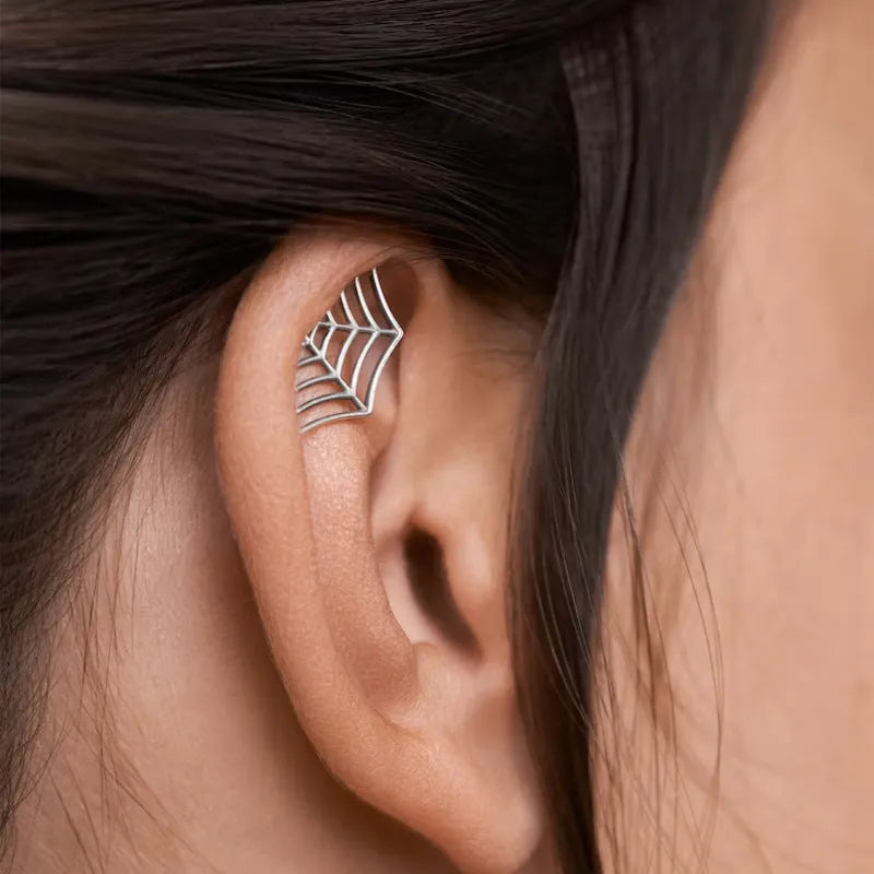 Close-up of a geometric spider web design on a gold-toned metal stud earring.