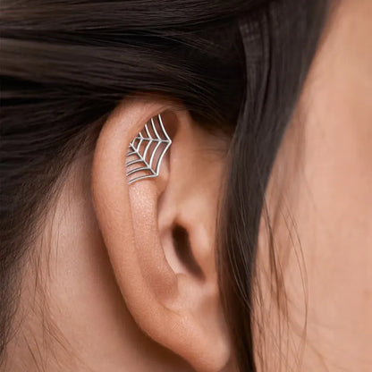Close-up of a geometric spider web design on a gold-toned metal stud earring.