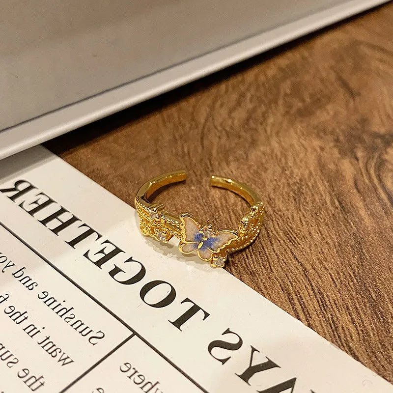 Copper butterfly women's ring with an open loop design on a plain background.