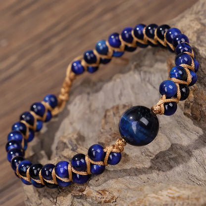 Close-up of a hand-woven geometric bracelet with a blue Tigereye stone on a wrist.