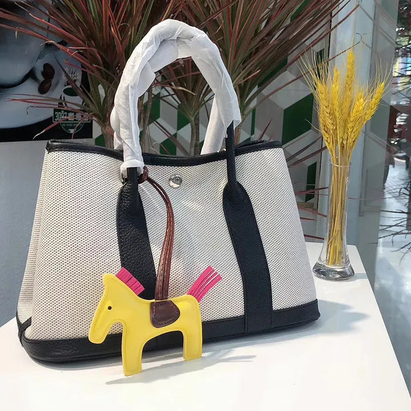 Canvas and leather tote bag in bucket shape with crossbody strap, shown in black, brown, gray or red colour options