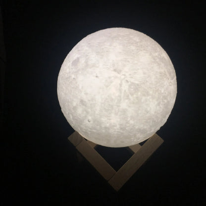3D printed white moon lamp on a wooden holder, showing detailed crater texture and soft LED glow.