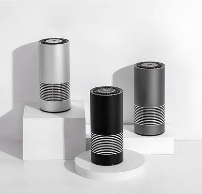 Compact black car air purifier with aluminium alloy and ABS construction, shown next to a car USB port.