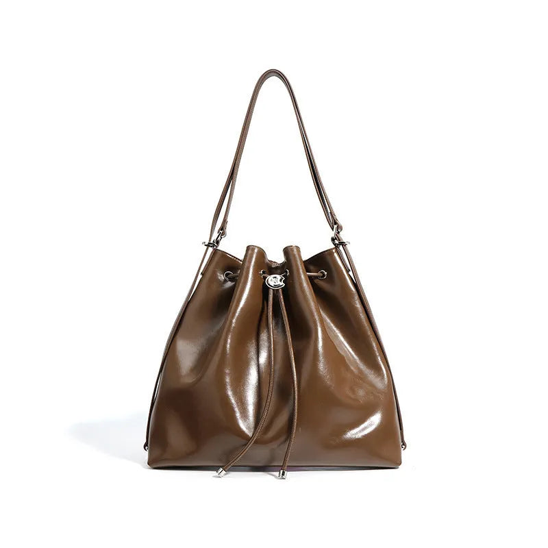 Brown genuine leather retro-style bucket bag with a single shoulder strap showing internal zipped compartments.