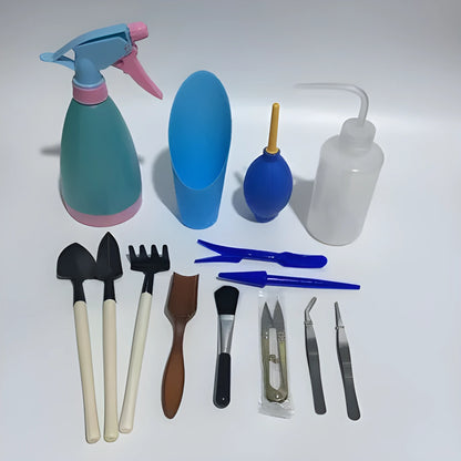 Succulent gardening tool set showing mini shovel, watering can, tweezers, and rake on a table.