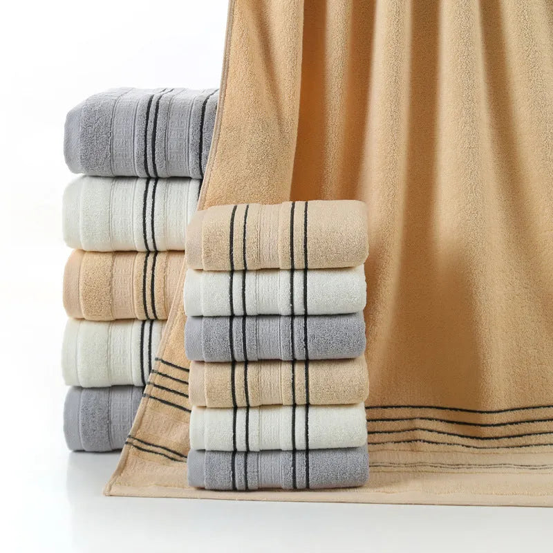 Household pure cotton towel set showing one large bath towel and two smaller hand towels in a neutral colour like grey or khaki.