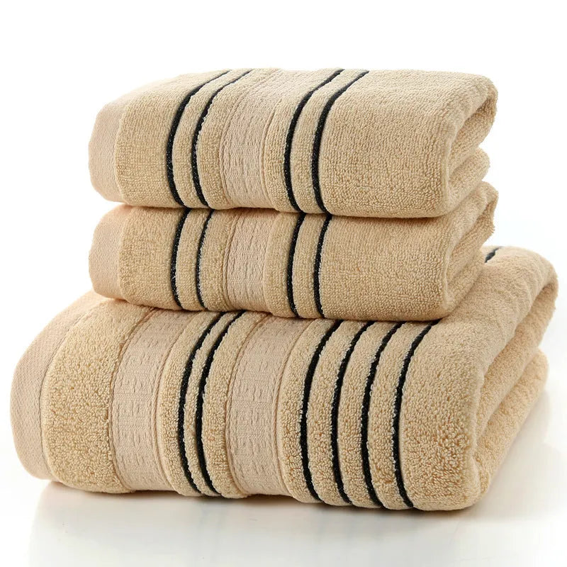 Household pure cotton towel set showing one large bath towel and two smaller hand towels in a neutral colour like grey or khaki.