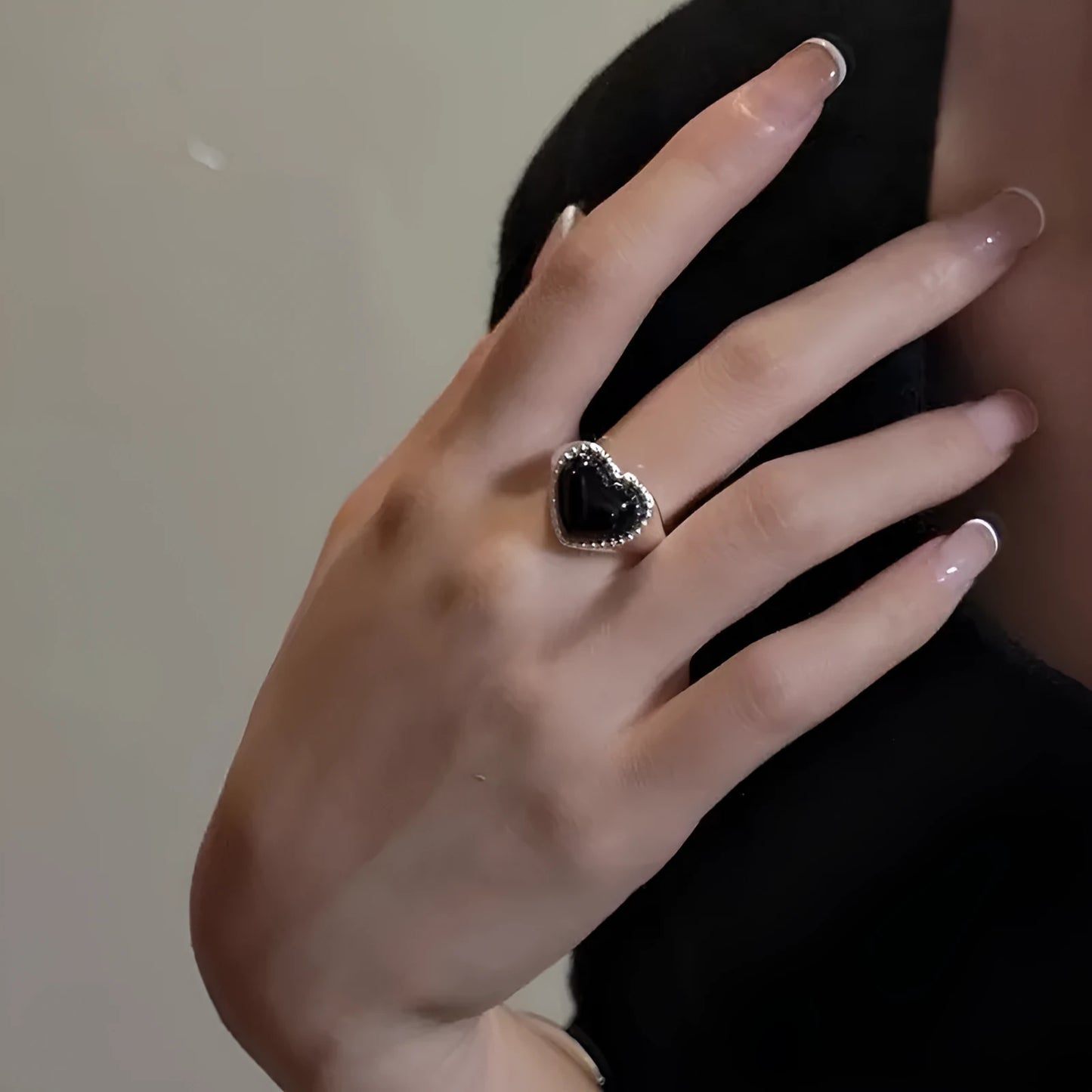 Adjustable sterling silver ring with a heart-shaped black agate stone in a niche setting on a woman's finger.