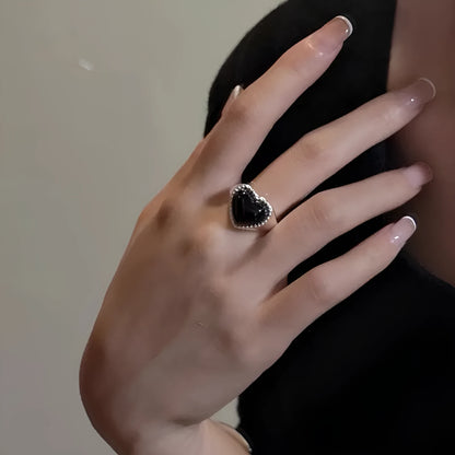 Adjustable sterling silver ring with a heart-shaped black agate stone in a niche setting on a woman's finger.