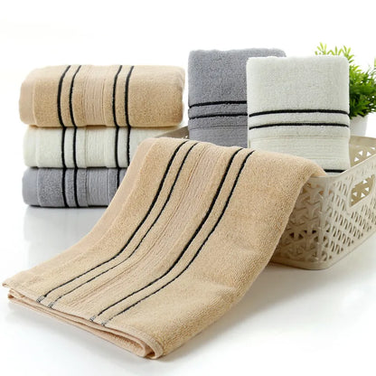 Household pure cotton towel set showing one large bath towel and two smaller hand towels in a neutral colour like grey or khaki.
