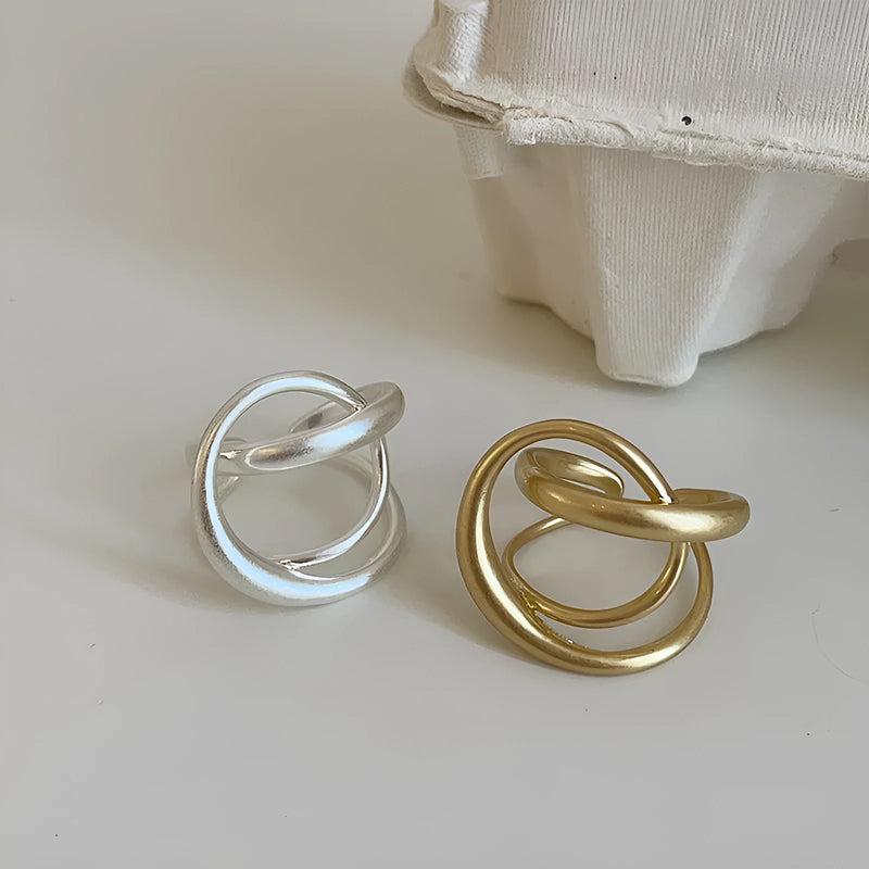 Three-dimensional interlaced matte metal open ring for women: a geometric design with electroplated real gold finish in gold or silver colour options, offering a contemporary jewellery piece with adjustable fit.