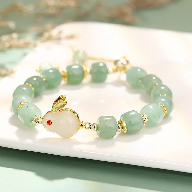 Adjustable rabbit charm bracelet with natural stone beads and gold plated details on a wrist.