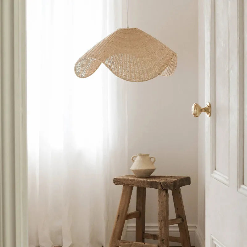 Handmade woven rattan and willow chandelier with warm LED light in a rustic setting.