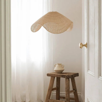 Handmade woven rattan and willow chandelier with warm LED light in a rustic setting.