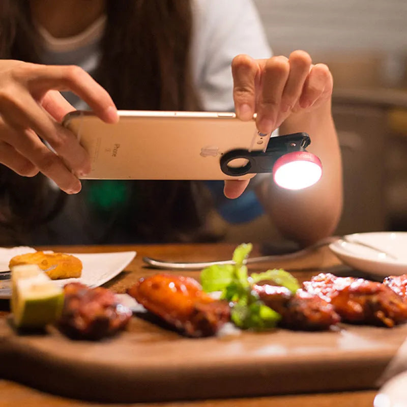 External wide-angle lens and colourful LED light ring attached to a smartphone via a universal mounting clip.