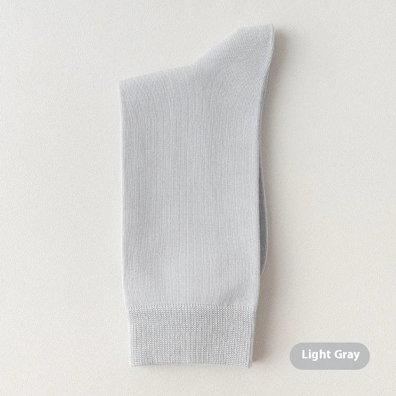 Pair of solid-colour men's mid-calf socks made from combed cotton on a wooden background