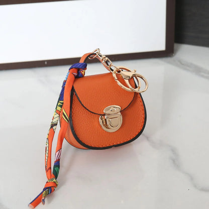 Solid colour PVC coin purse keychain shown in saddle bag black, orange, brown, red, grey, and pink.