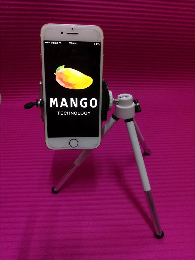 Black adjustable desktop phone holder with extended arm on a wooden desk, holding a mobile phone.
