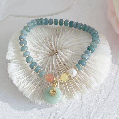 Simple blue jade bracelet with gourd charm, peace buckle, and adjustable cord on woman's wrist