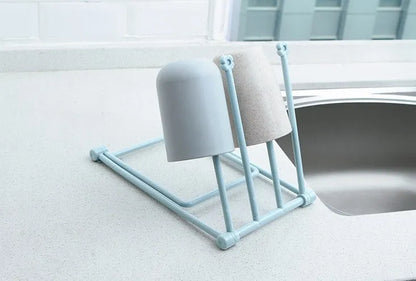 Foldable plastic dishcloth shelf organiser in light blue mounted on a wall.