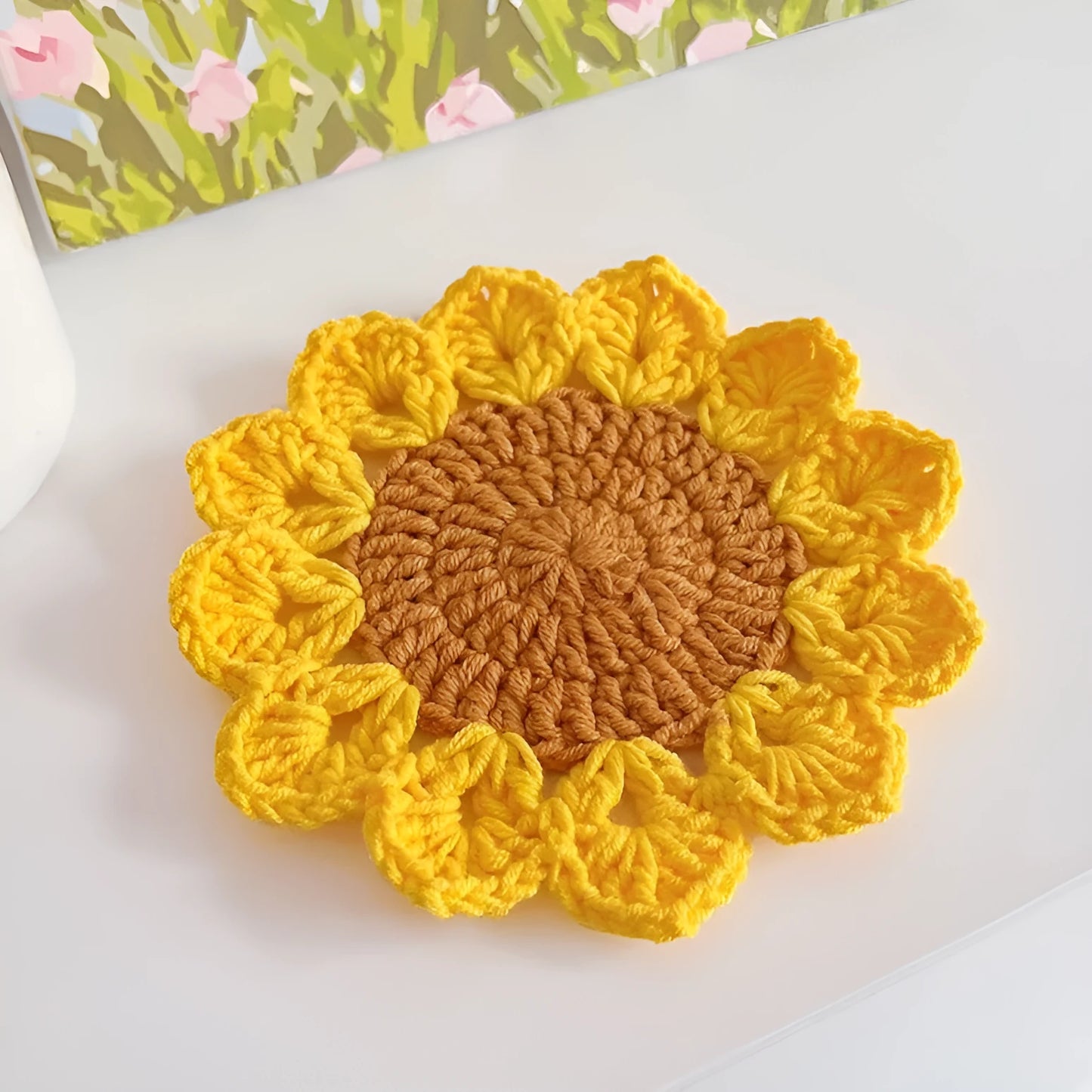 Hand-woven circular wool coaster with a flower pattern, part of a set for table protection.