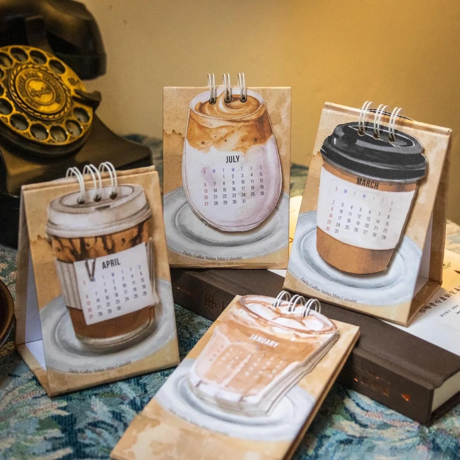Set of four different themed 2025 mini paper desk calendars on a desk.