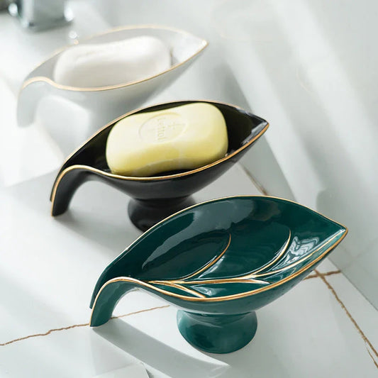A ceramic soap dish with a sleek leaf-shaped design, featuring a suction cup base for secure and tidy placement in the bathroom or kitchen.