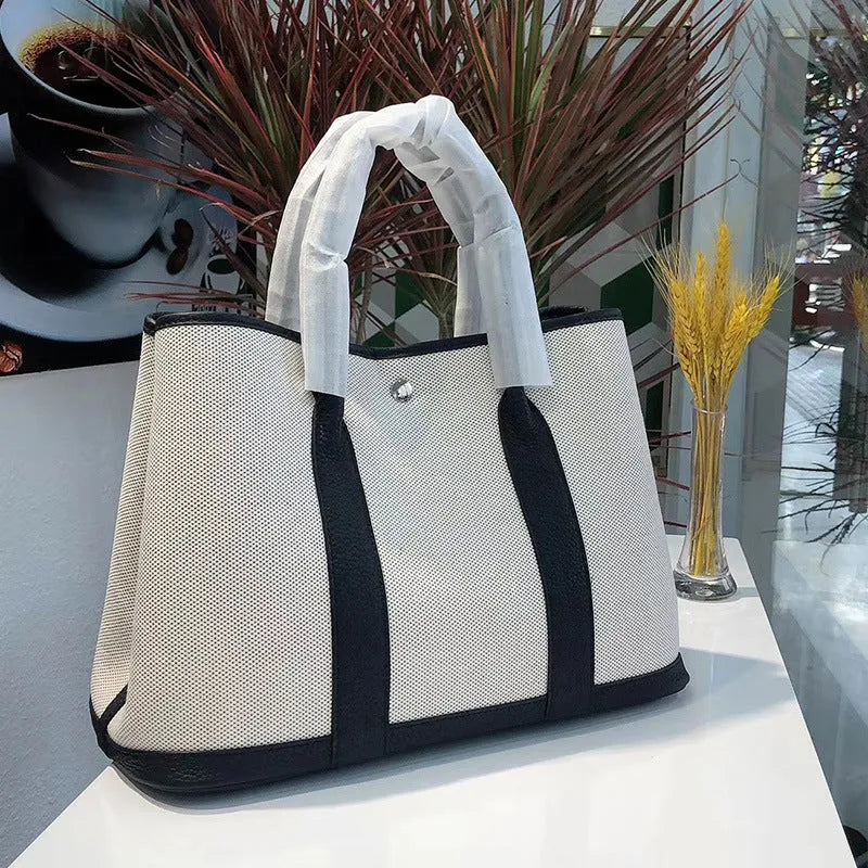 Canvas and leather tote bag in bucket shape with crossbody strap, shown in black, brown, gray or red colour options