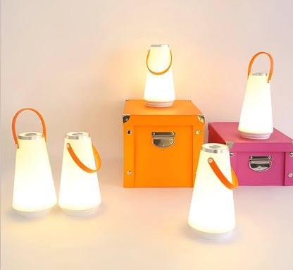 White rechargeable LED lantern with USB cable on a bedside table.