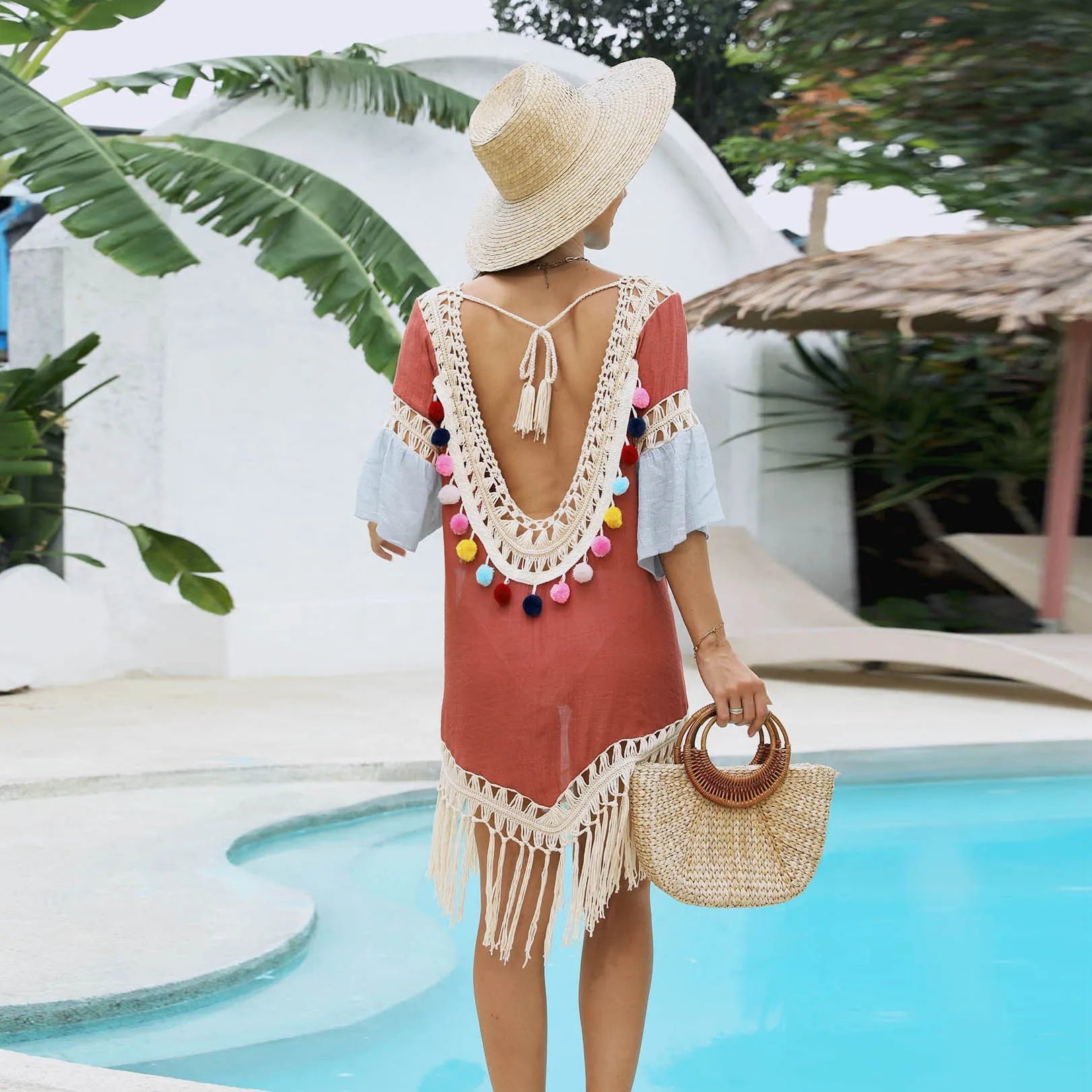 Orange floral print beach overskirt with hand-crochet detail and tassel trim, worn as a cover-up over swimwear.