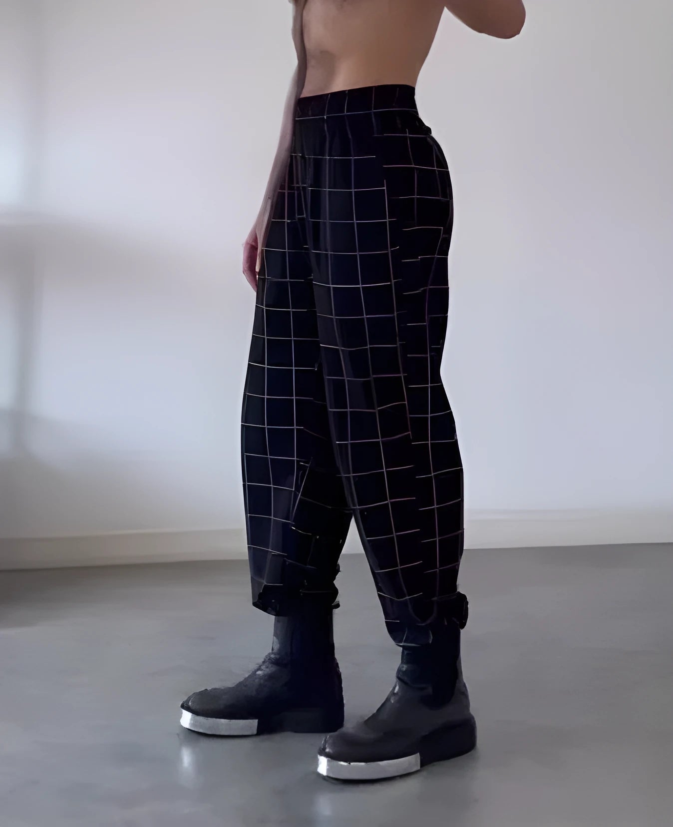 Man wearing grey plaid trousers with a distinctive apron-front design detail.