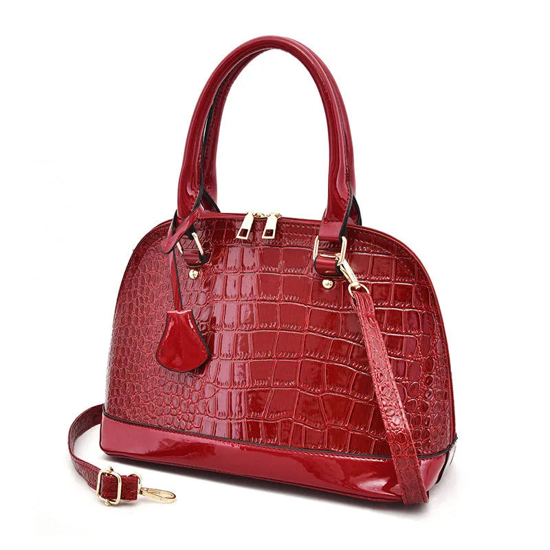 Large shiny black PU leather crossbody bag with a shell shape, shown from the front.