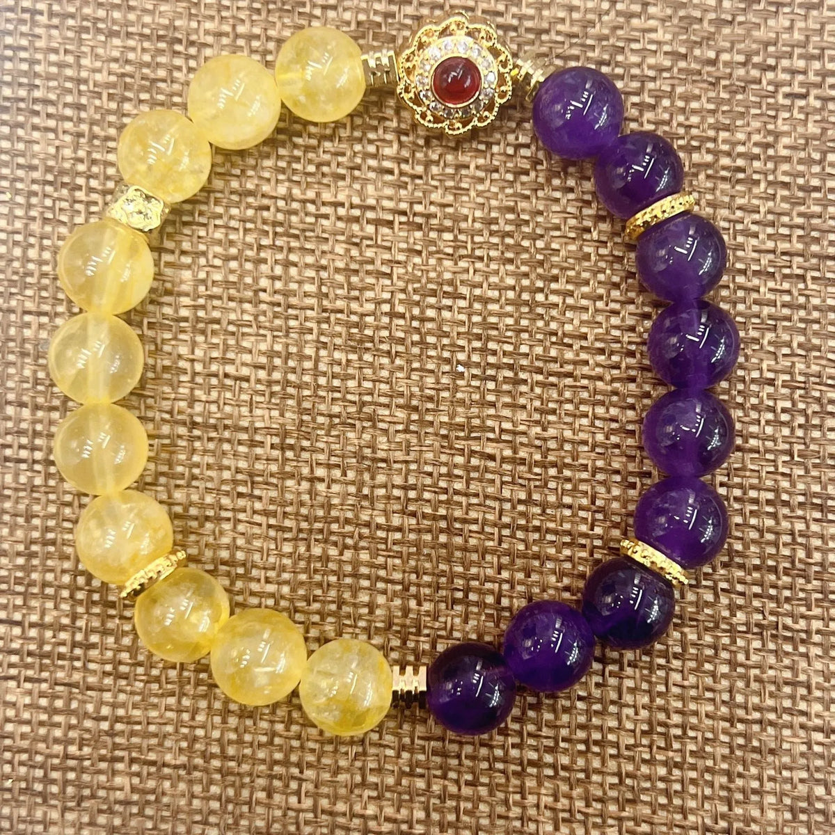 Handmade women's bracelet with yellow and purple amethyst crystals on wrist.
