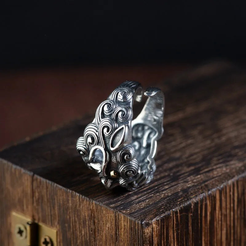 Domineering open ring with engraved animal pattern on wide sterling silver band, shown on a finger.