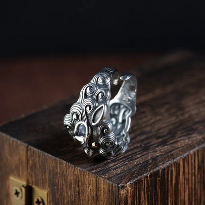 Domineering open ring with engraved animal pattern on wide sterling silver band, shown on a finger.