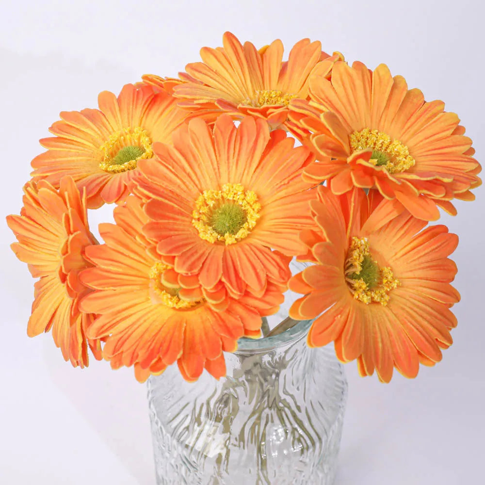 Silk artificial flower bouquet in a white polyurethane pot on a wooden table.