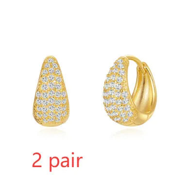 Pair of golden geometric clip-on earrings with a round design and screw-back mechanism on a white background.