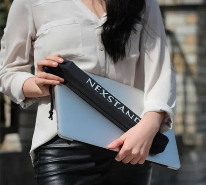 Black folding portable laptop stand made of reinforced nylon, shown folded to its slim 4cm profile.