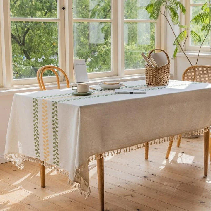 A beautifully embroidered tablecloth with a delicate floral and leaf pattern, perfect for dining and outdoor events.
