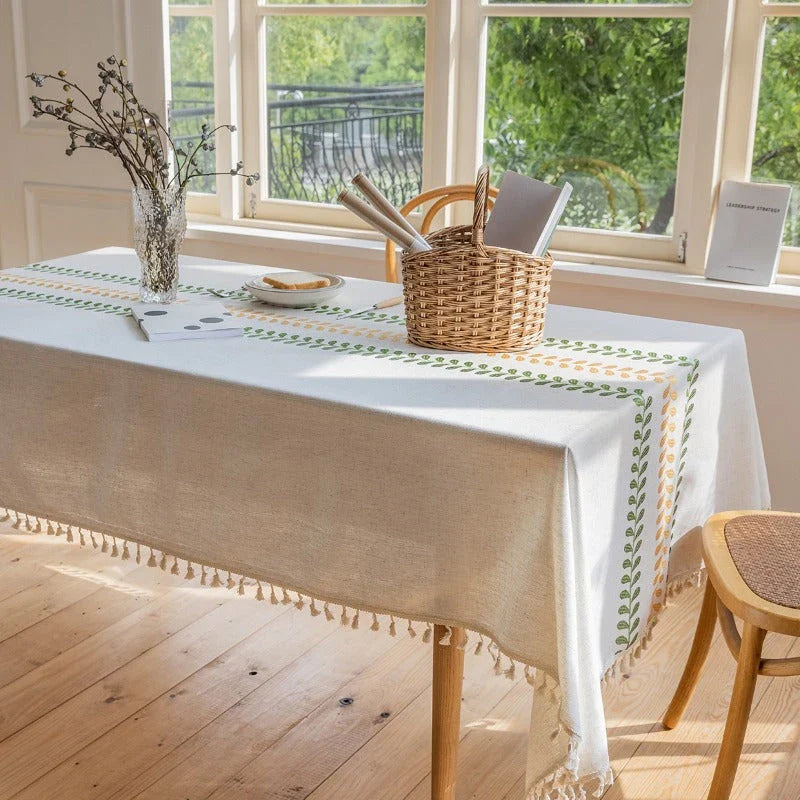 A beautifully embroidered tablecloth with a delicate floral and leaf pattern, perfect for dining and outdoor events.