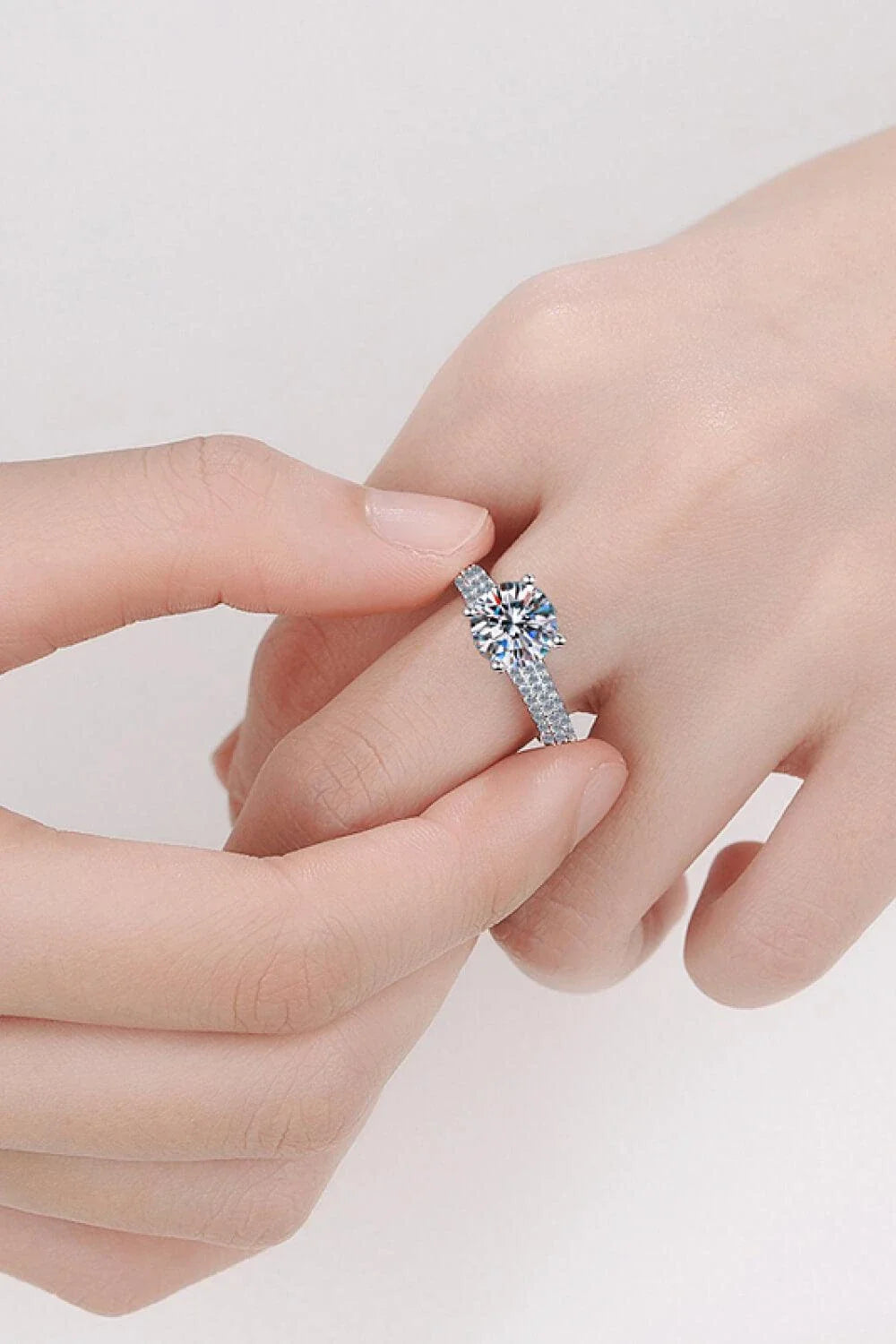 Elegant 4-prong moissanite and sterling silver ring with rhodium plating and zircon accent stones