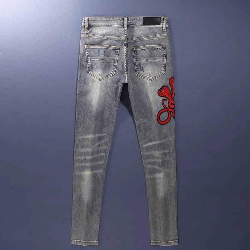 Men's slim fit cotton jeans with washed-out finish, hole patch detailing, and embroidery in old colour