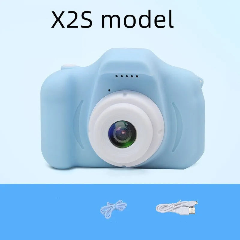 X2 HD mini digital camera for kids in silicone case with lanyard, shown capturing photo on 2-inch screen.