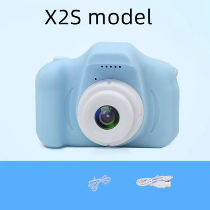 X2 HD mini digital camera for kids in silicone case with lanyard, shown capturing photo on 2-inch screen.