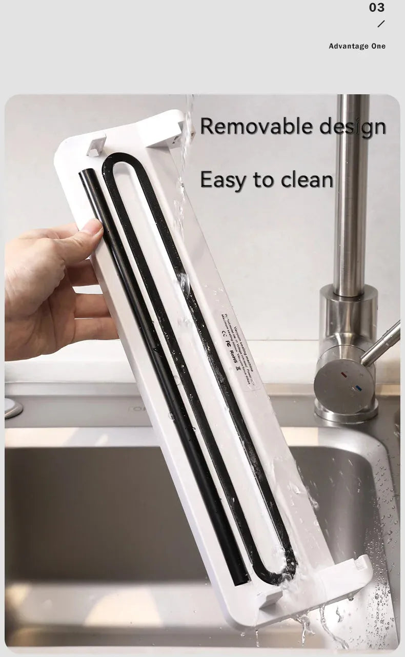 Black automatic vacuum sealer with 30cm sealing bar on kitchen counter next to vacuum-sealed food packages