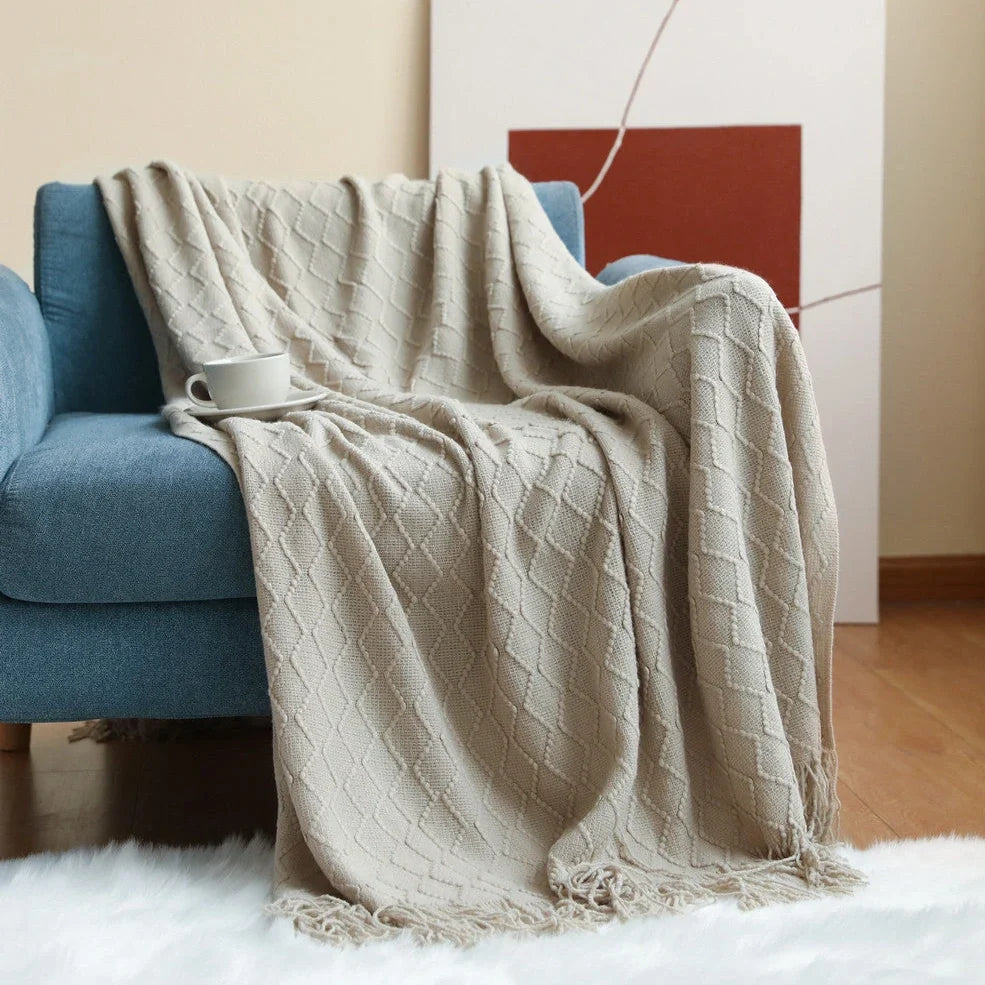 Nordic knitted blanket in beige colour showing open knit pattern on grey sofa