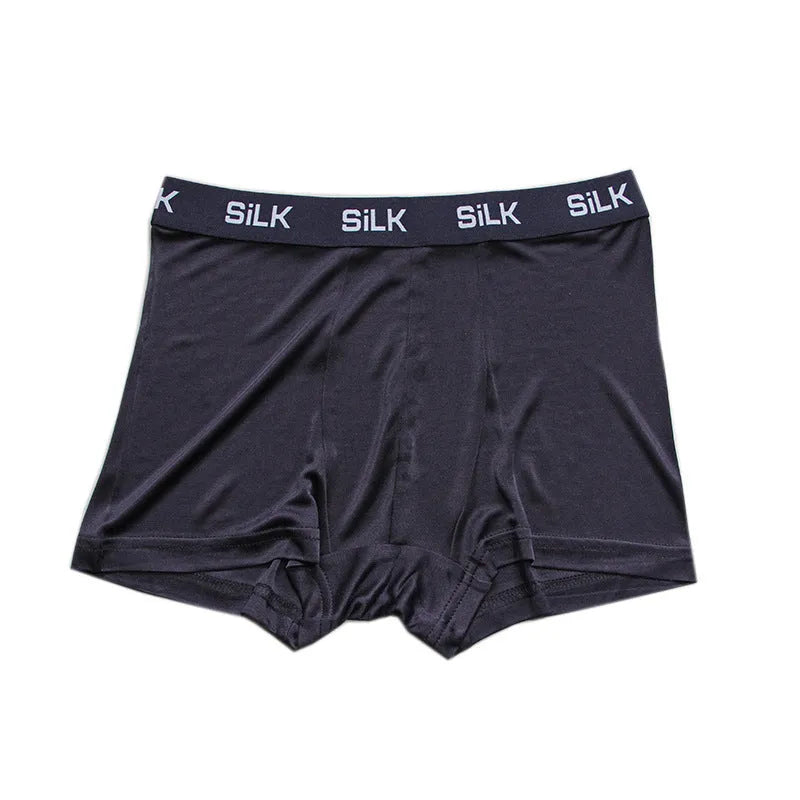 Man wearing loose-fit mid-waist shorts in navy blue silk fabric.